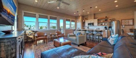 A spacious living area with a large sofa, a dining table, and a kitchen in the background.