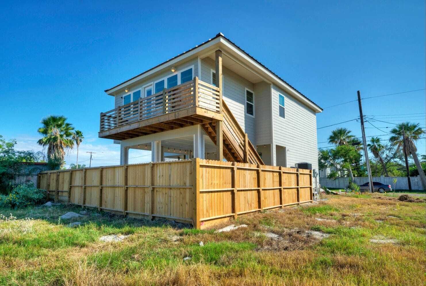 A two-story house with a wooden deck and a staircase leading to the upper floor.