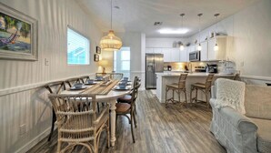 A dining area with a long table, wicker chairs, and a hanging light fixture. - 2 Blocks to the Beach, Patio, Resort Pool w/ Slide Tranquil Tides by Avantstay (Port Aransas)