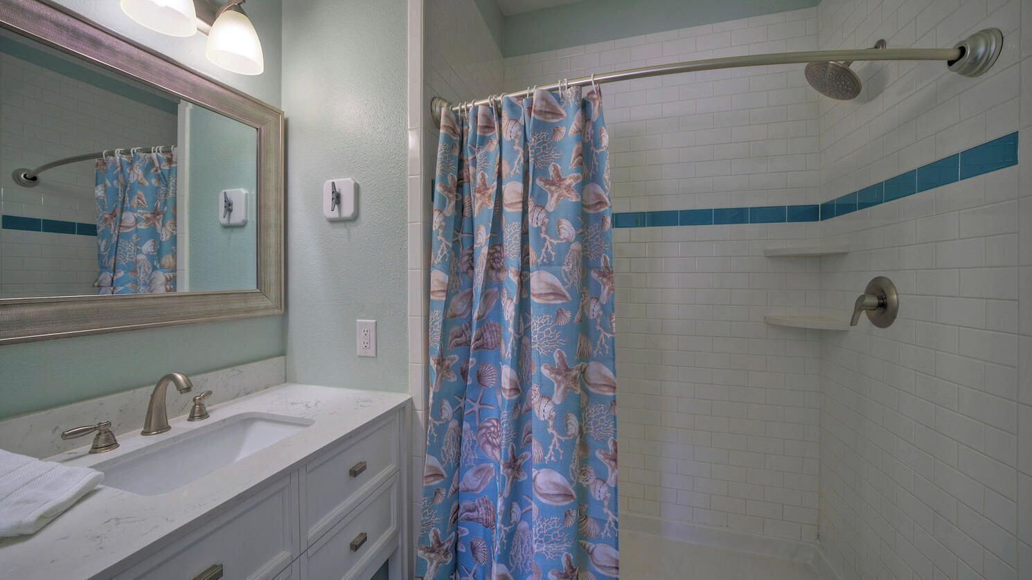 A bathroom with a shower, a sink, a mirror, and a towel rack.