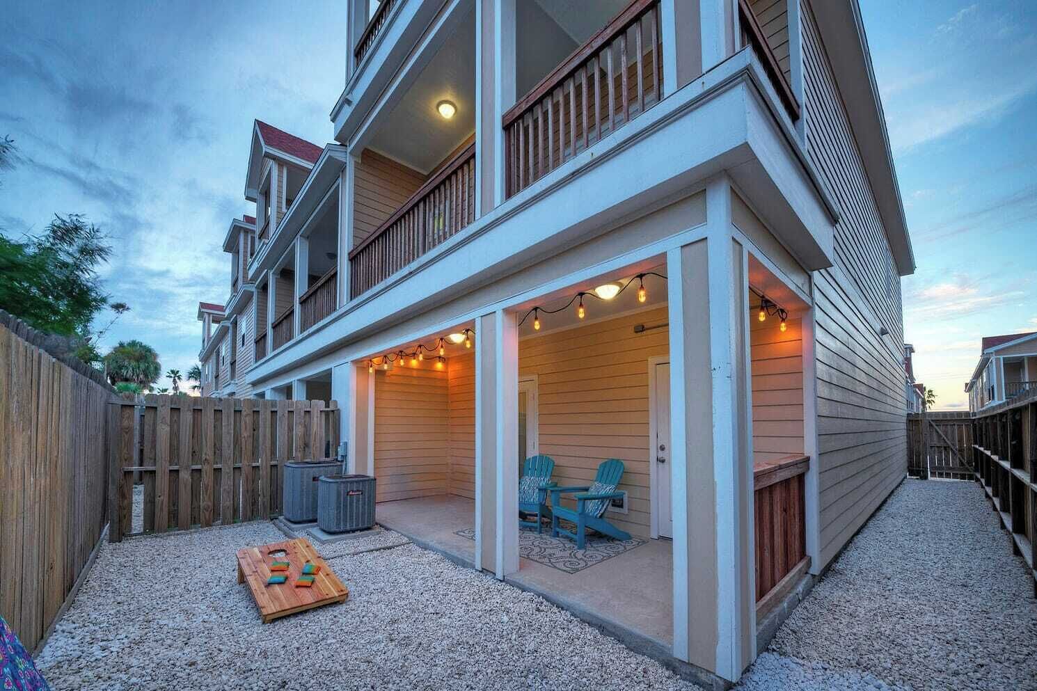 Edificio de dos pisos con un patio techado que incluye mesas al aire libre y luces colgantes.
