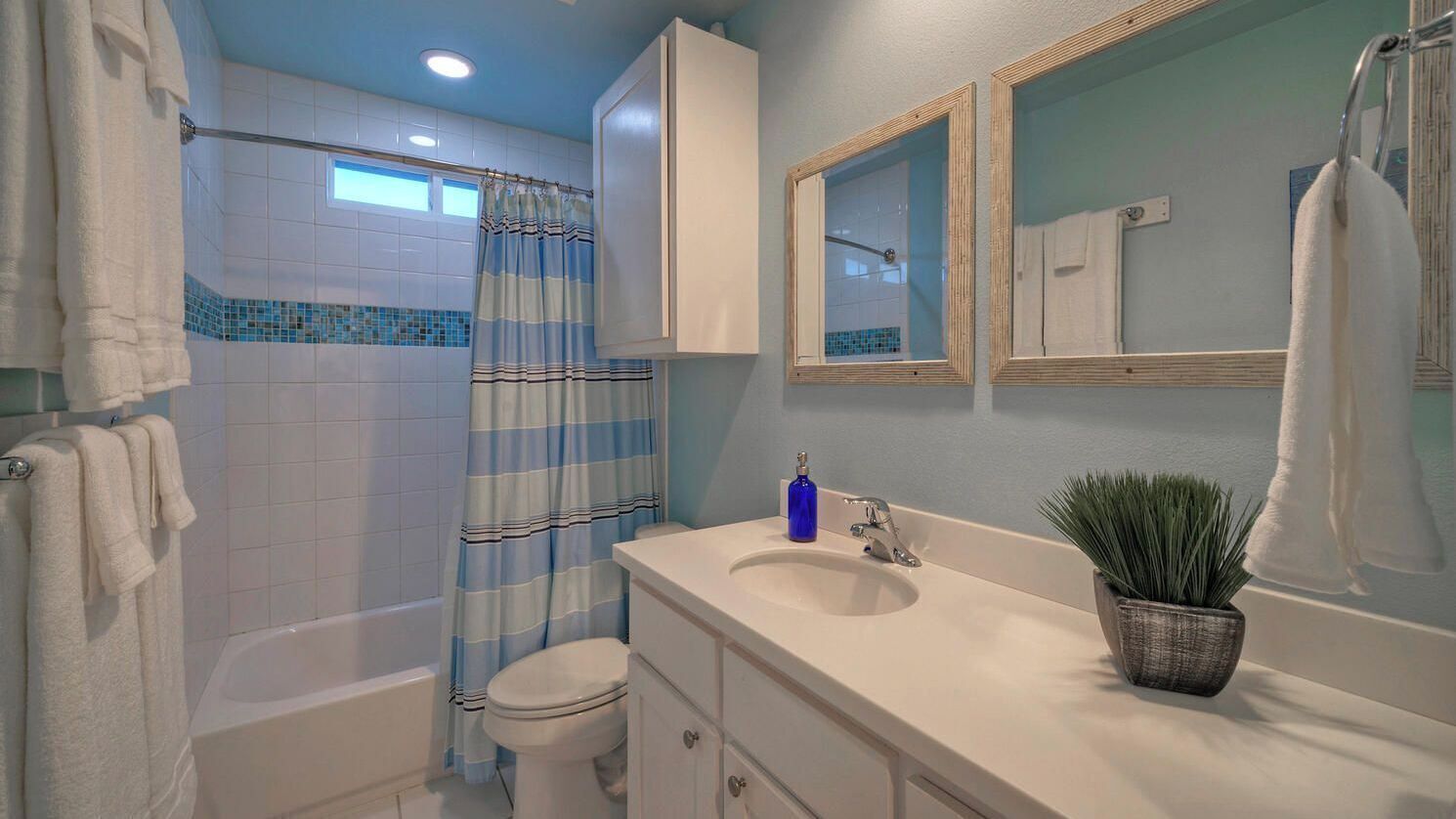 Une salle de bain équipée d’une baignoire, de toilettes, d’un rideau de douche, d’un lavabo, d’un miroir et de serviettes.