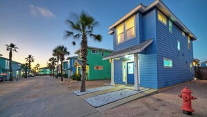A two-story building with a blue exterior, a visible entrance, and a red fire hydrant in the foreground. - Private Yard, Shared Pool Near the Beach Bluetique Hotel by Avantstay (Port Aransas)