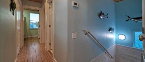 A hallway with wooden floors, a handrail, and walls decorated with fish.