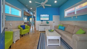A living room with a TV, two sofas, a coffee table, and a ceiling fan. - Private Yard, Shared Pool Near the Beach Bluetique Hotel by Avantstay (Port Aransas)