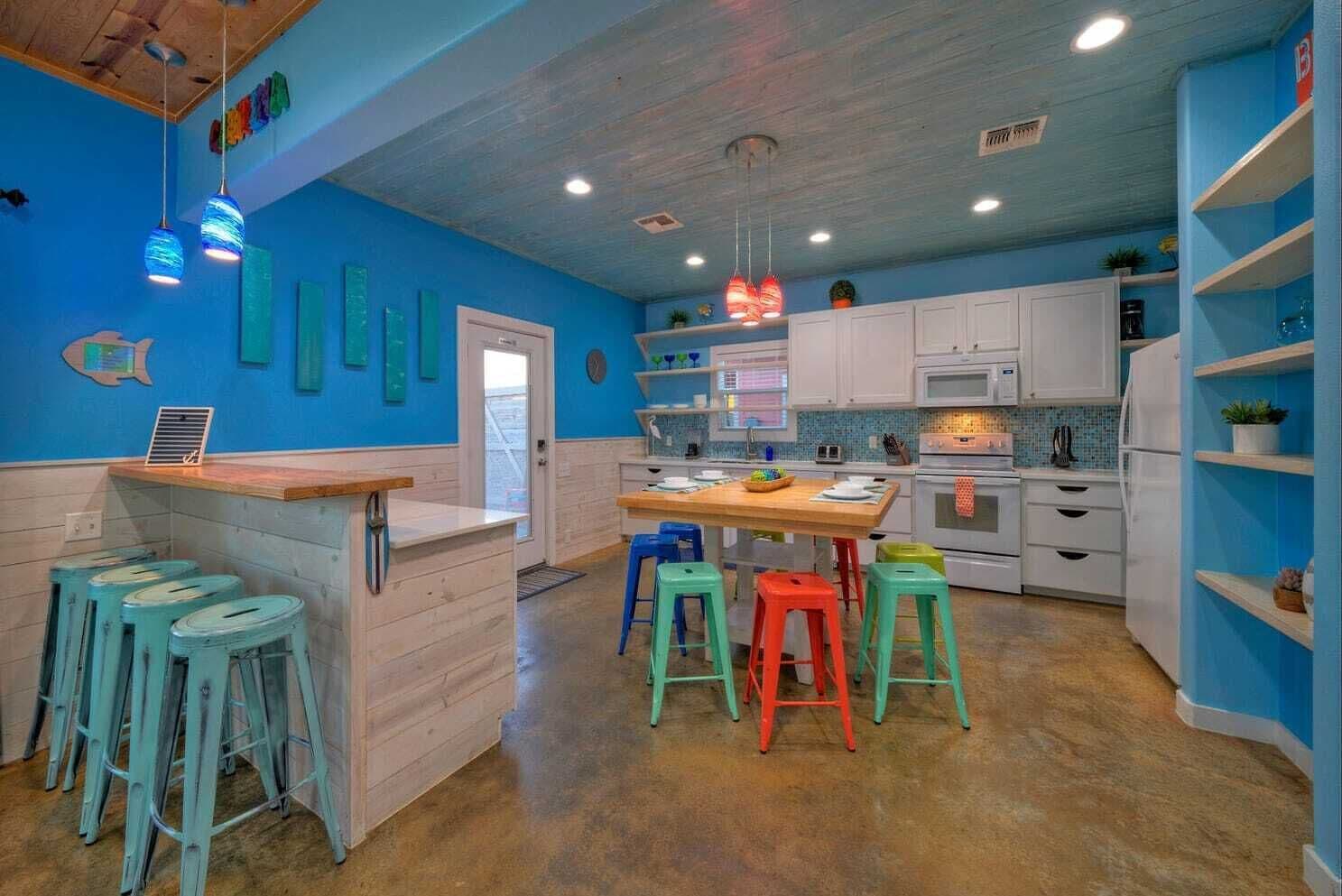 A kitchen with blue walls, white cabinets, and colorful stools.