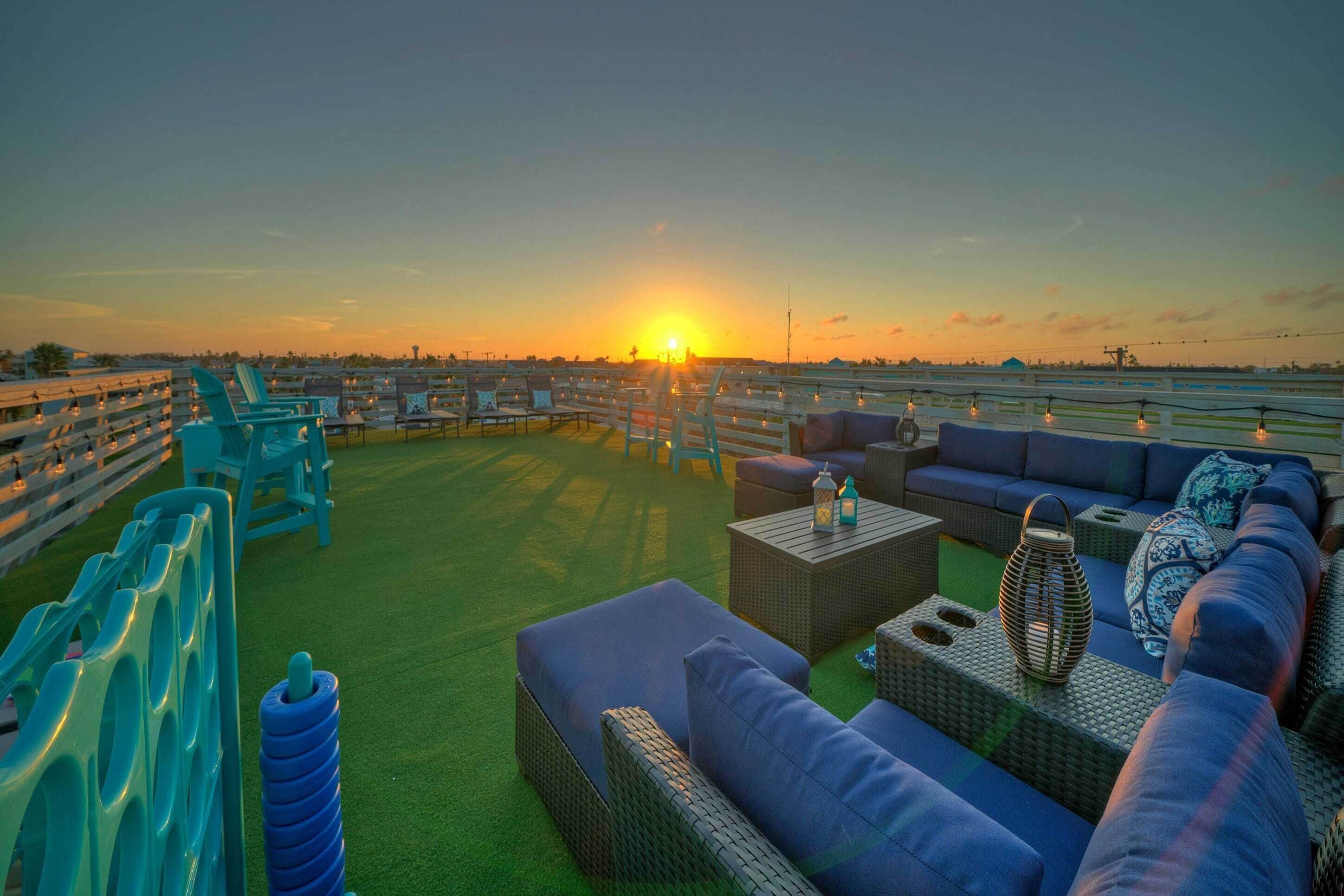 A rooftop terrace with seating arrangements and a sunset view.