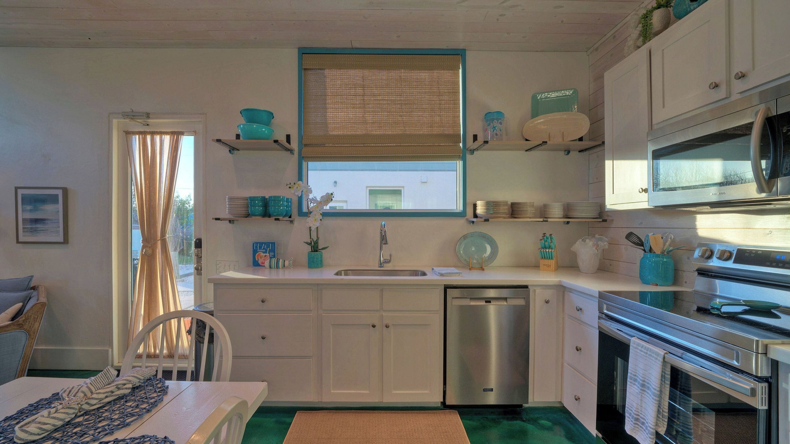 A compact kitchen with white cabinets, a stainless steel sink, and a built-in oven.