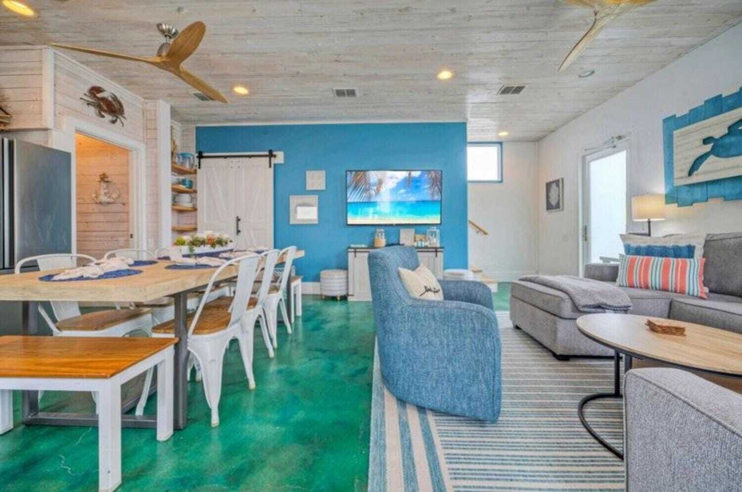 A spacious living area with a dining table, chairs, and a blue accent wall.