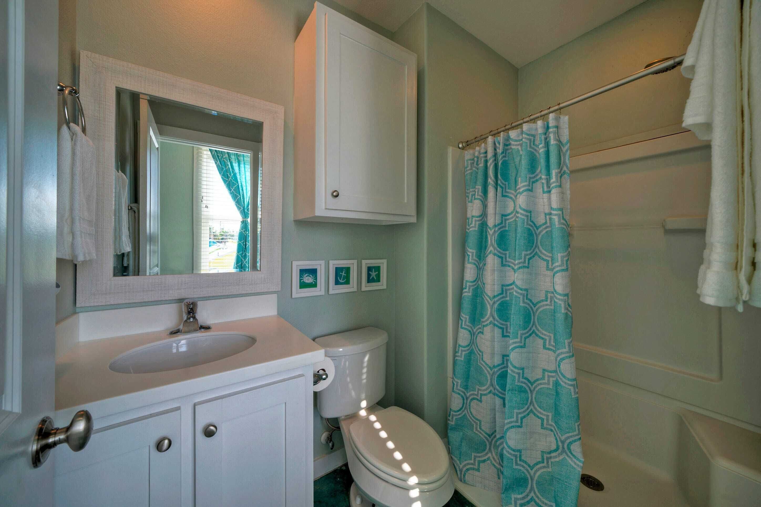 A bathroom with a white sink, a toilet, a mirror, and a shower curtain.