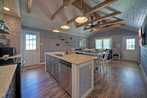 A spacious kitchen with a large island, wooden beams, pendant lighting, and a dishwasher. - Aloha Ohana by Avantstay Private Pool Near Beach (Port Aransas)