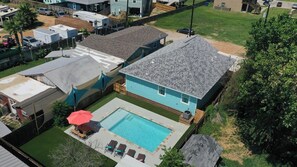 En bostadsfastighet med en swimmingpool, en inhägnad trädgård och ett hus med ett sluttande tak.