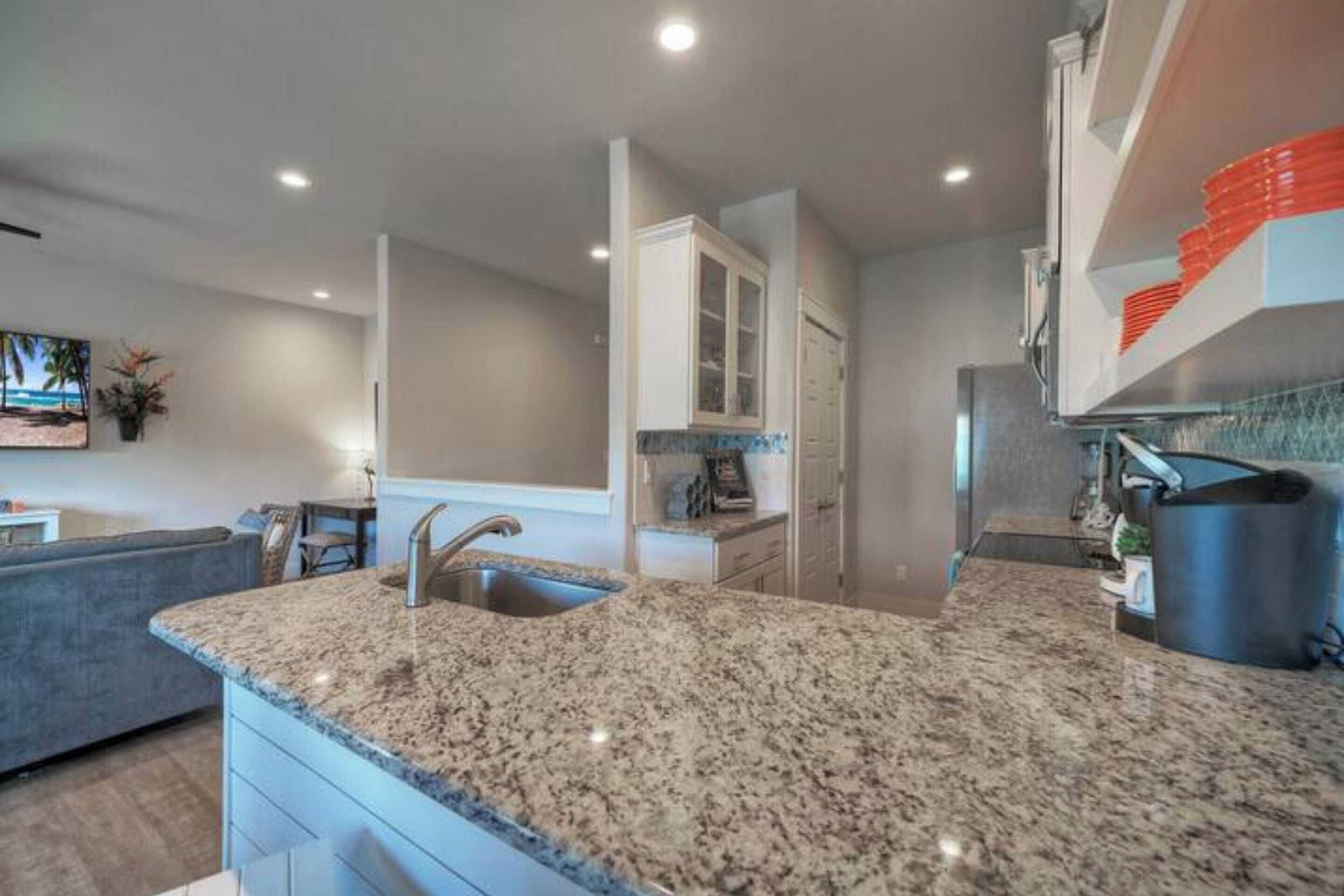 A modern kitchen with granite countertops, white cabinetry, and a built-in oven.