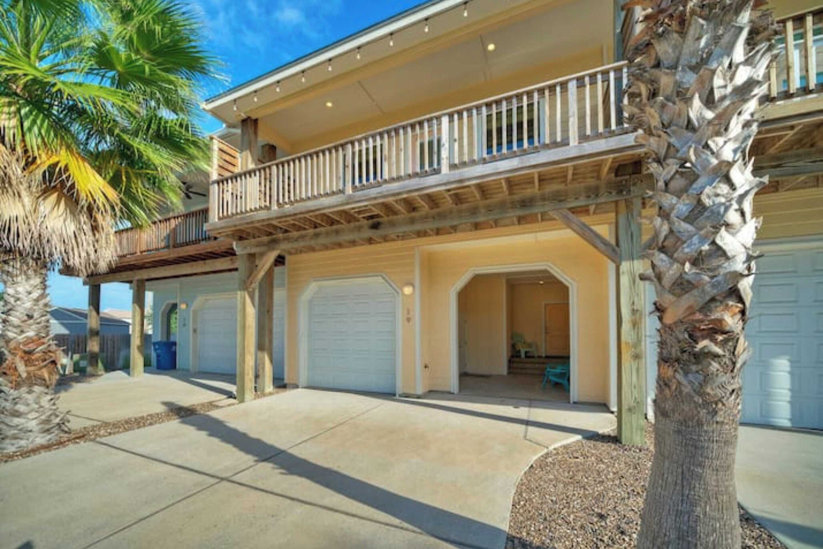 A two-story house with a balcony, a garage, and a palm tree.