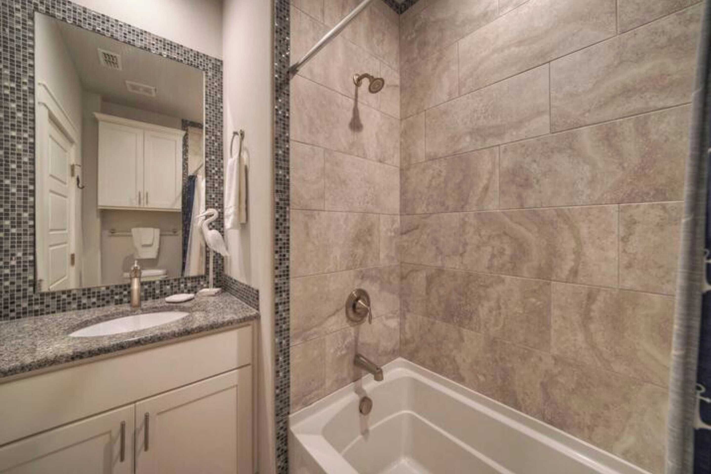 Een badkamer met een wastafel, spiegel en douche.