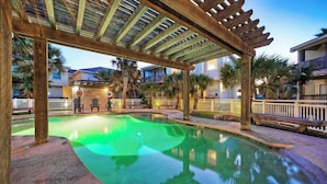 A pool area with a wooden pergola, palm trees, and a white fence. - Pool, Walk to Old Town + Eateries, Nightlife, Shopping Rock N Reelby Avantstay (Port Aransas)