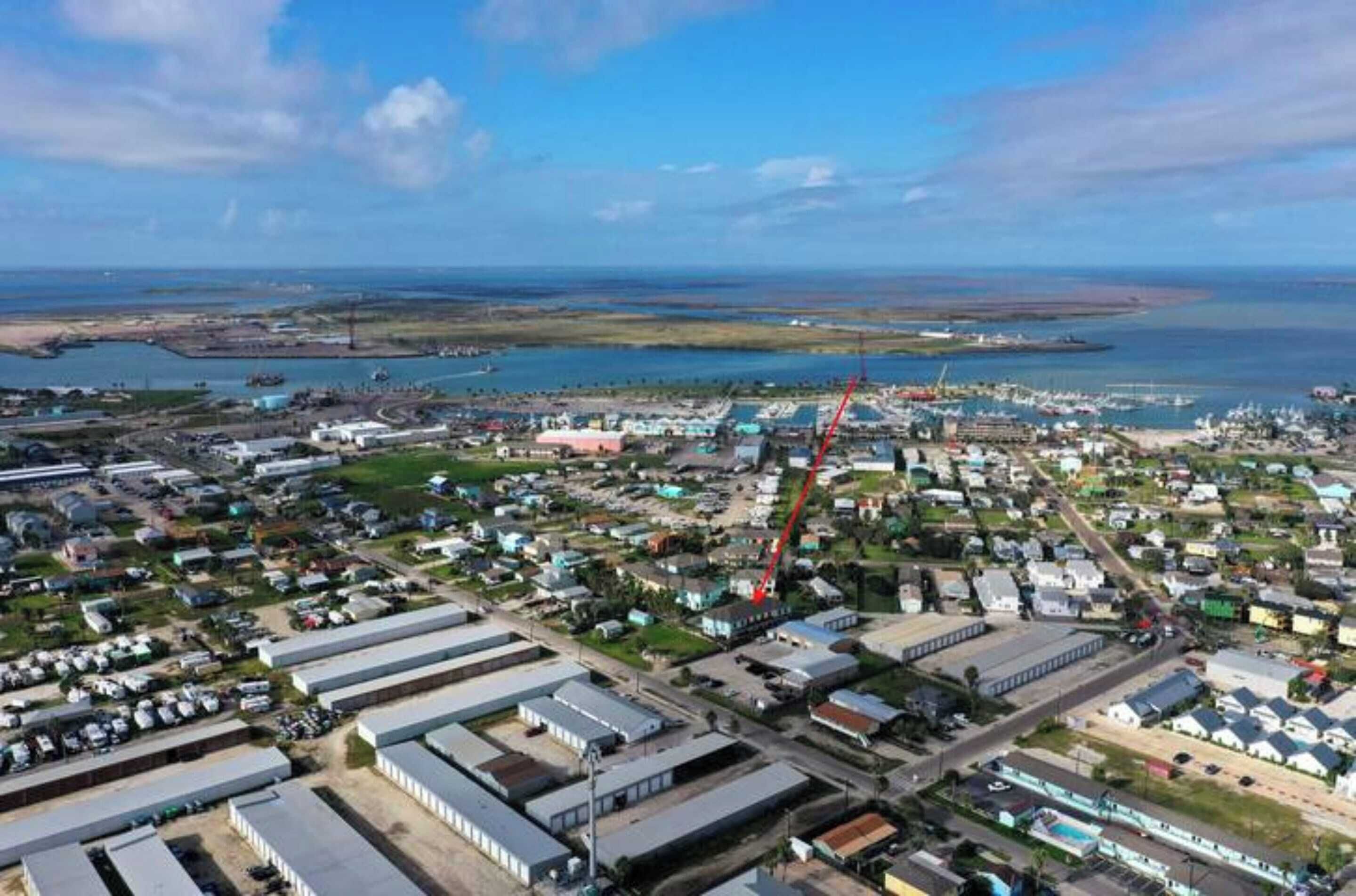 An aerial view of a coastal town with industrial buildings, residential areas, and a marina.