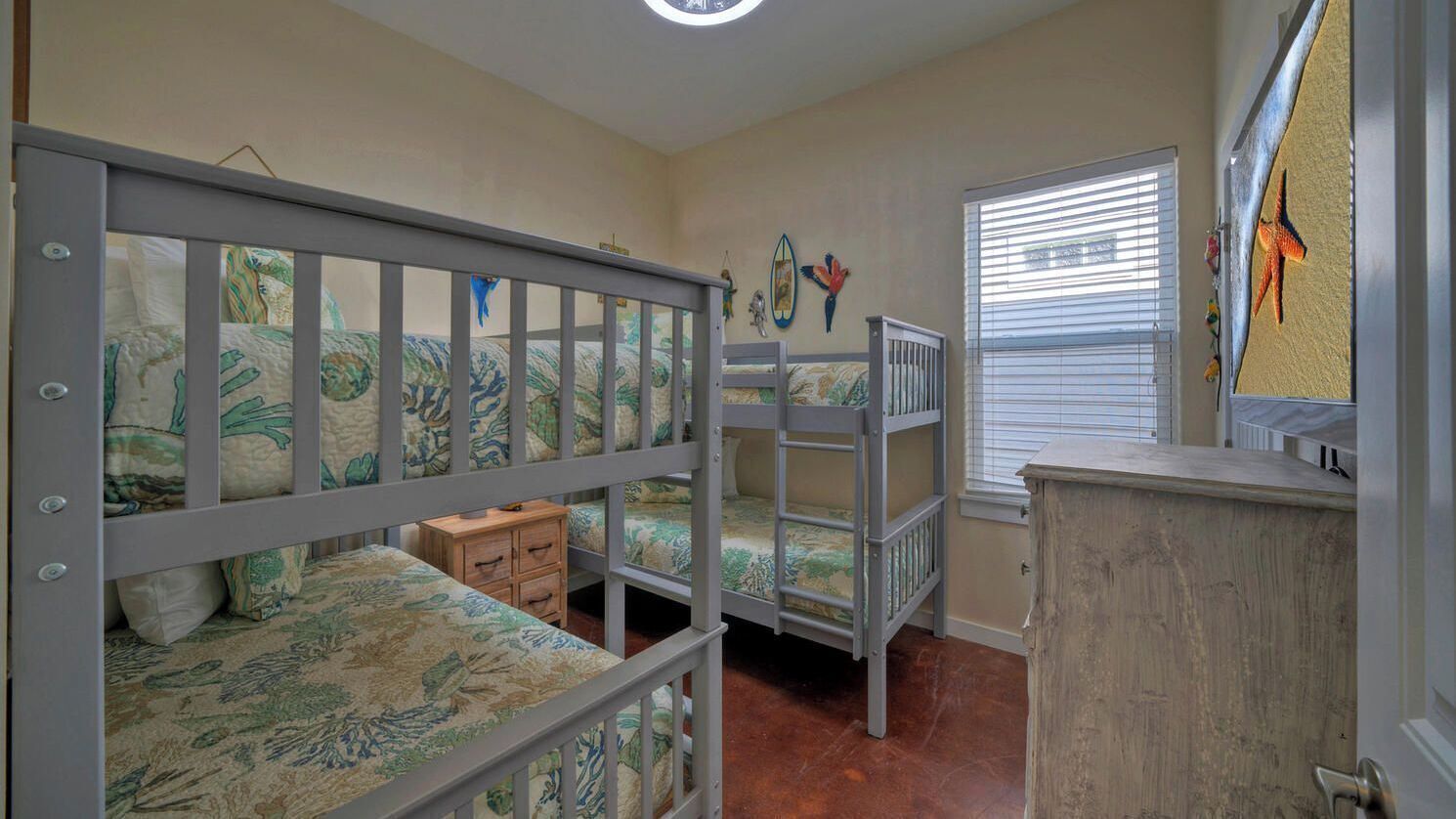 A child's bunk bed room with a dresser and a window with blinds.