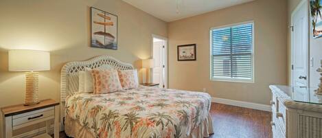 A bedroom with a bed, nightstands, a ceiling fan, a window with blinds, and a door.