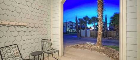 An outdoor patio area with two metal chairs, a small table, and a decorative wall with a scalloped pattern.