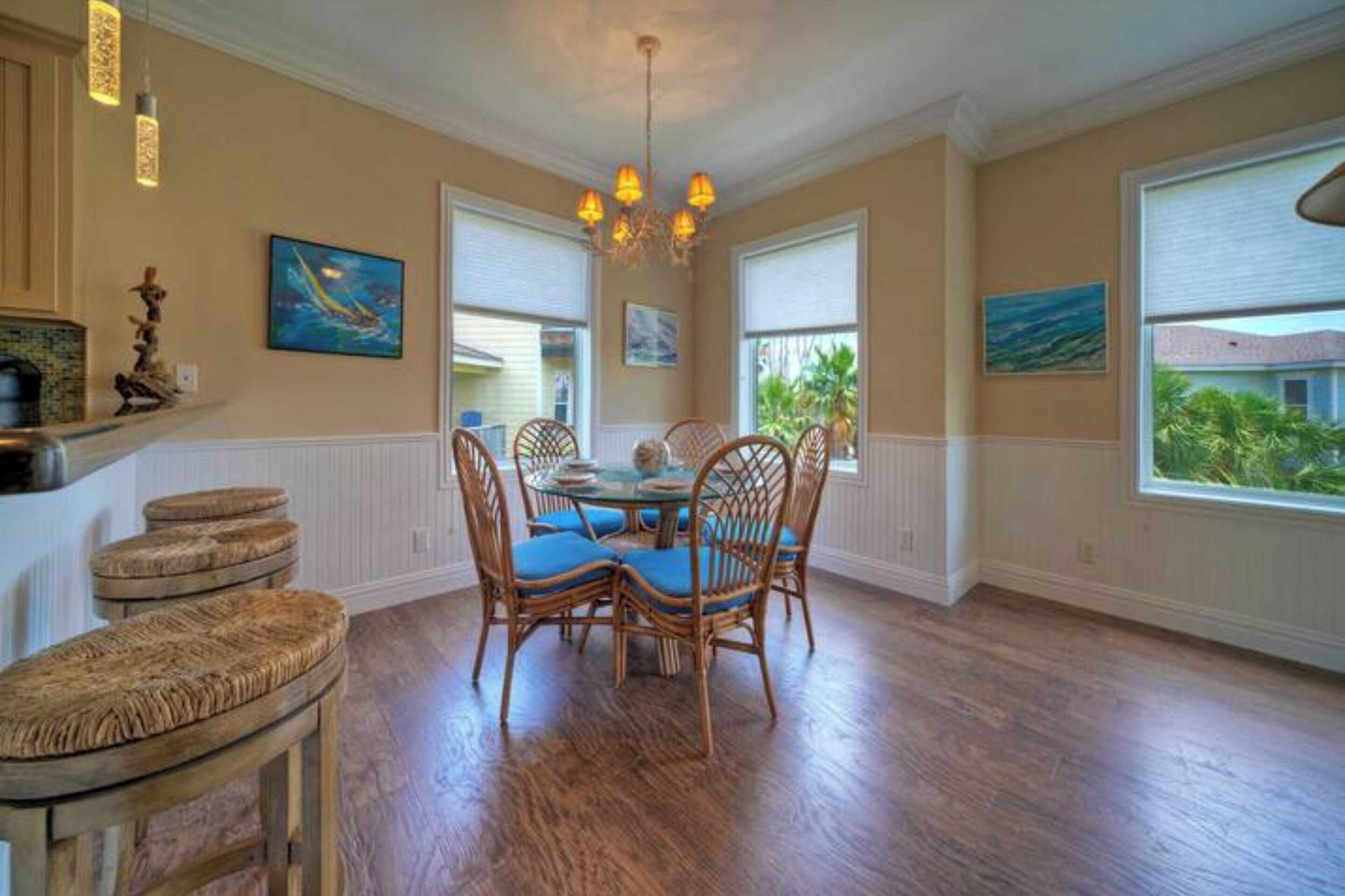 A dining area with a round table, four chairs, and a chandelier.