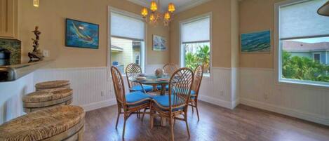 A dining area with a round table, four chairs, and a chandelier.