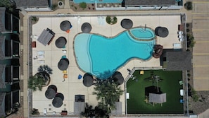 An aerial view of a swimming pool area with lounge chairs, a deck, and a small building. - Coastal Vibe by Avantstay Sunset at the Pool and Playscape (Port Aransas)