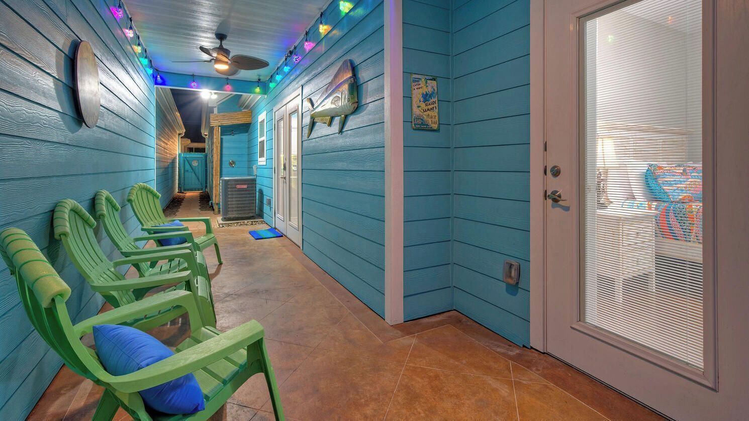 A hallway with teal walls, green chairs, and a door with a window.