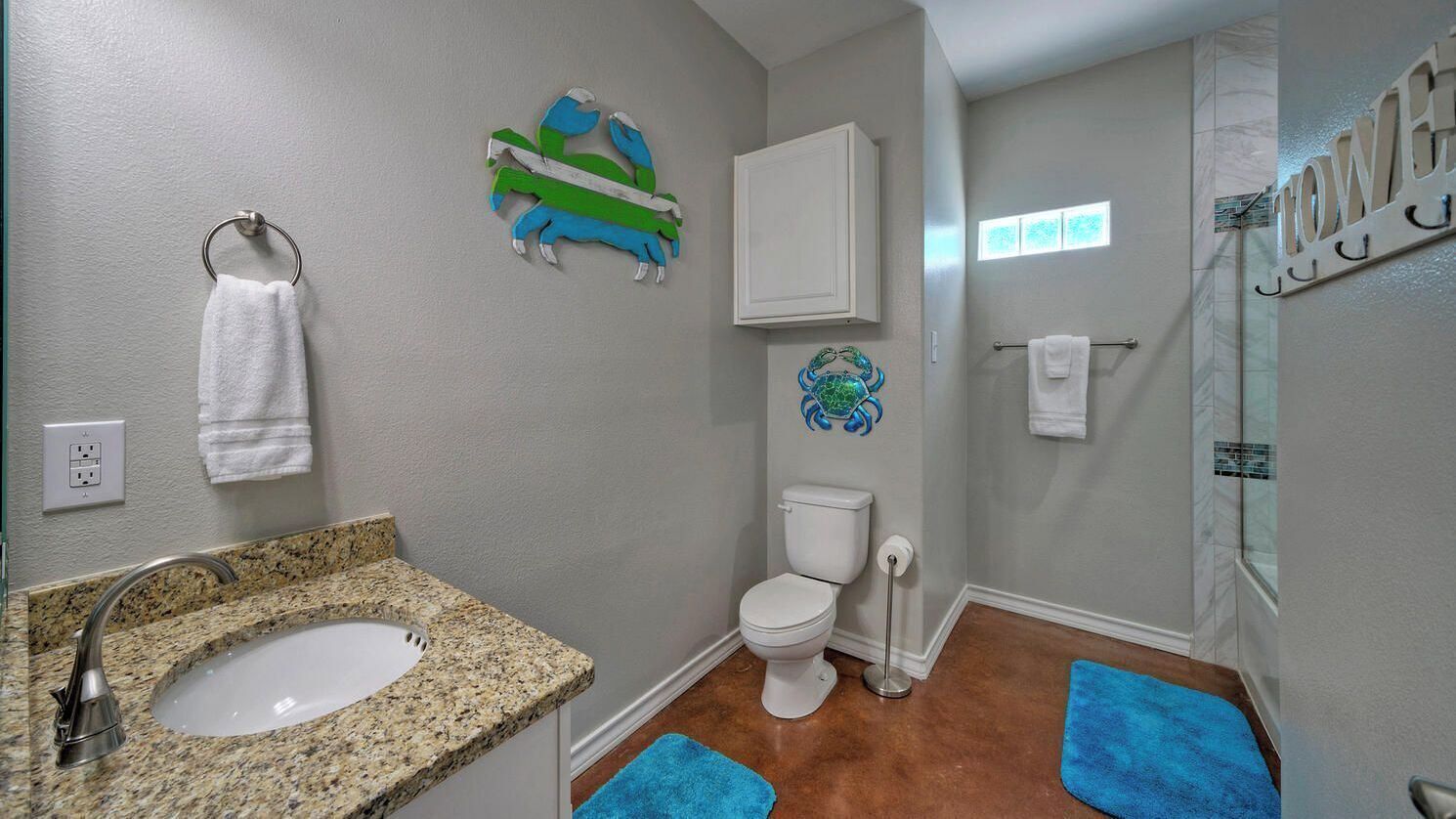 A bathroom with a granite sink, white toilet, and a shower area.