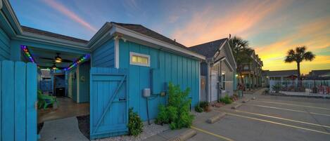 A blue building with a garage, a parking lot, and a sunset in the background.