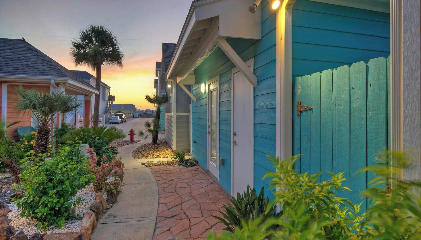 A residential street with houses, a pathway, and a sunset.