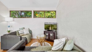 A modern living room with a grey sofa, a small round table, and a TV on a cabinet.