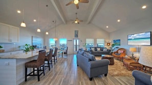 A spacious living area with a dining area, a sofa, and a television. - Pelican's Porch by Avantstay Private Pool, Views (Port Aransas)