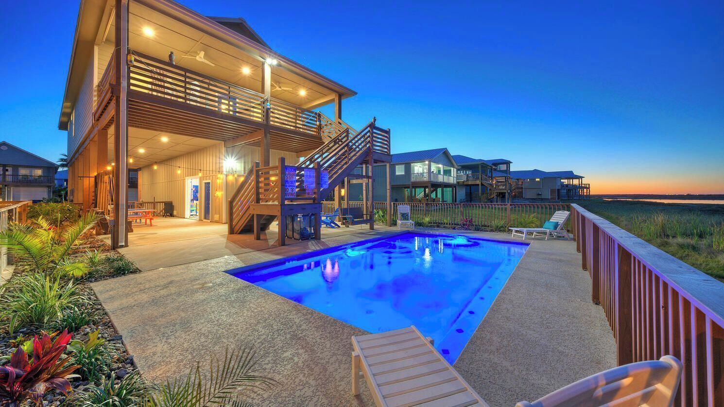 A modern house with a swimming pool, outdoor seating, and a view of the ocean.