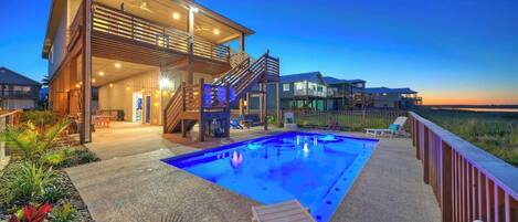 A modern house with a swimming pool, outdoor seating, and a view of the ocean.