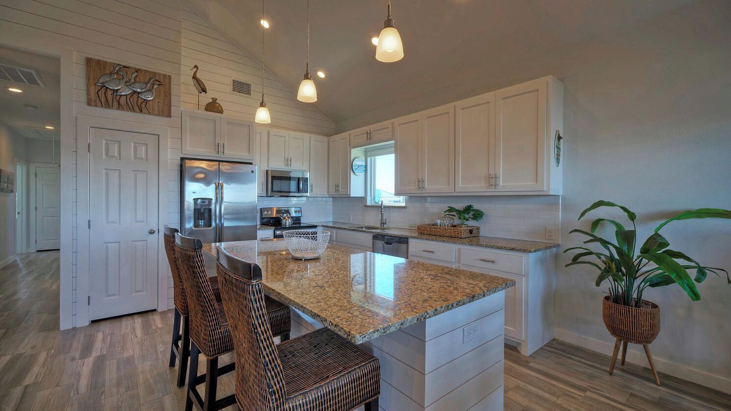 A kitchen with white cabinets, a granite countertop, and a central island with seating.