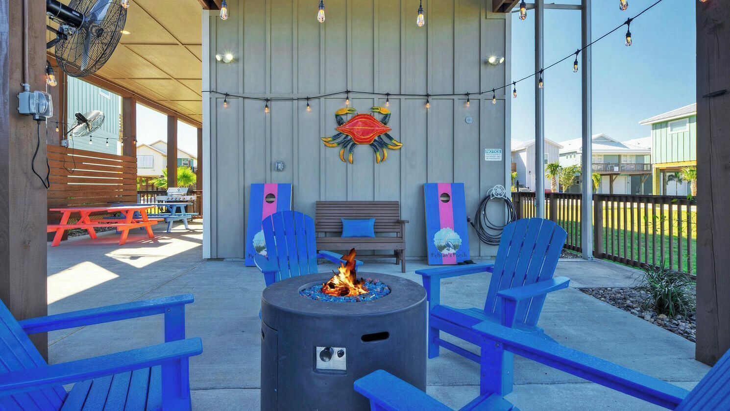 An outdoor seating area with a fire pit, blue chairs, and a wooden bench.