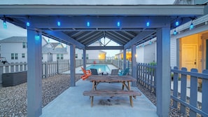 A covered outdoor area with a pool, picnic table, and chairs. - Newly Built, Pool, Walk to Old Town Eats+marina Shorely Goodness by Avantstay (Port Aransas)