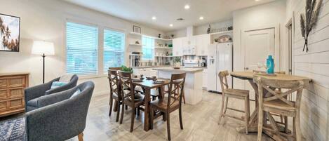 A modern kitchen with white cabinets, a wooden dining table, and a small island.