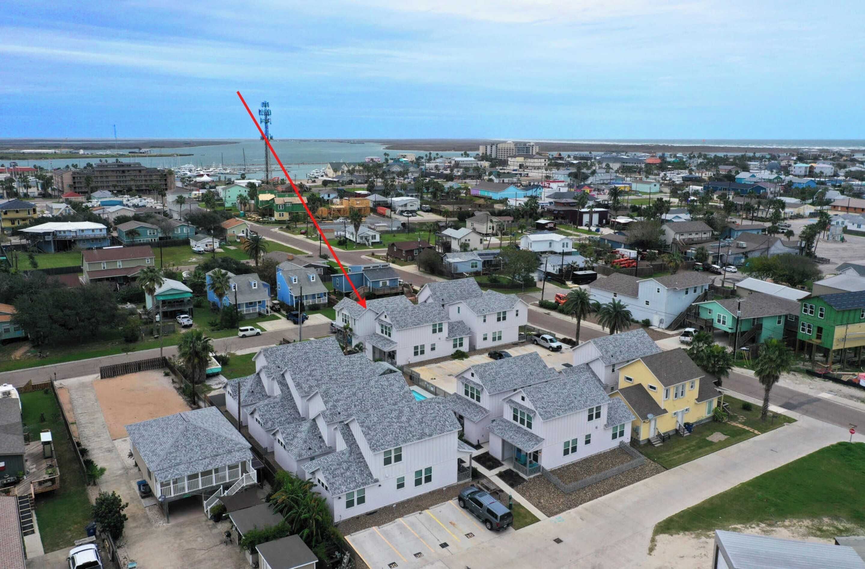 A residential area with houses, a beach, and a pier in the background.