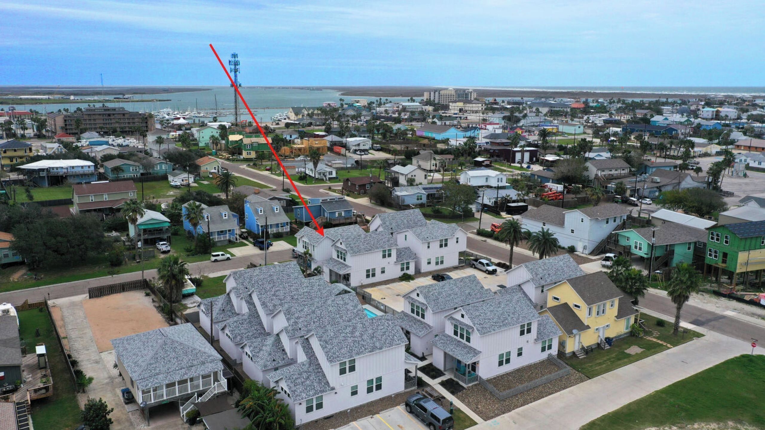 A residential area with houses, a clear sky, and a body of water in the background.