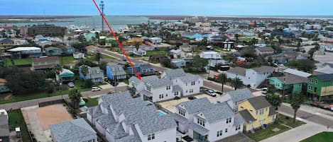 A residential area with houses, a clear sky, and a body of water in the background.