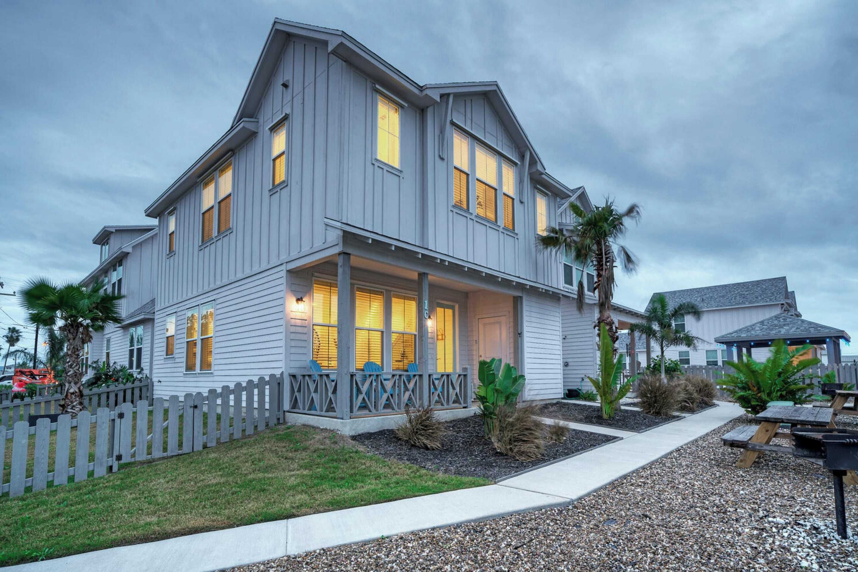 A two-story house with a porch, a picket fence, and a well-maintained lawn.