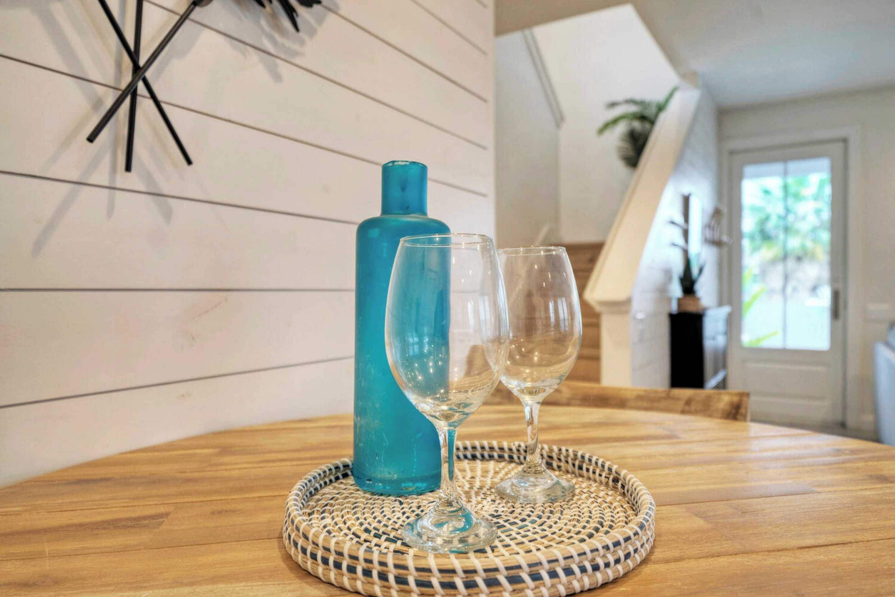 A wooden table with a woven placemat, a blue bottle, and two empty wine glasses.