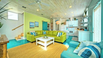 A living room with a green sofa, a white coffee table, and a blue sofa.