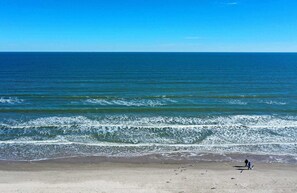 A beach with waves, a clear sky, and a person walking. - Rooftop Patio w/ View, Pool, Near the Beach Lost Shaker of Salt by Avantstay (Port Aransas)