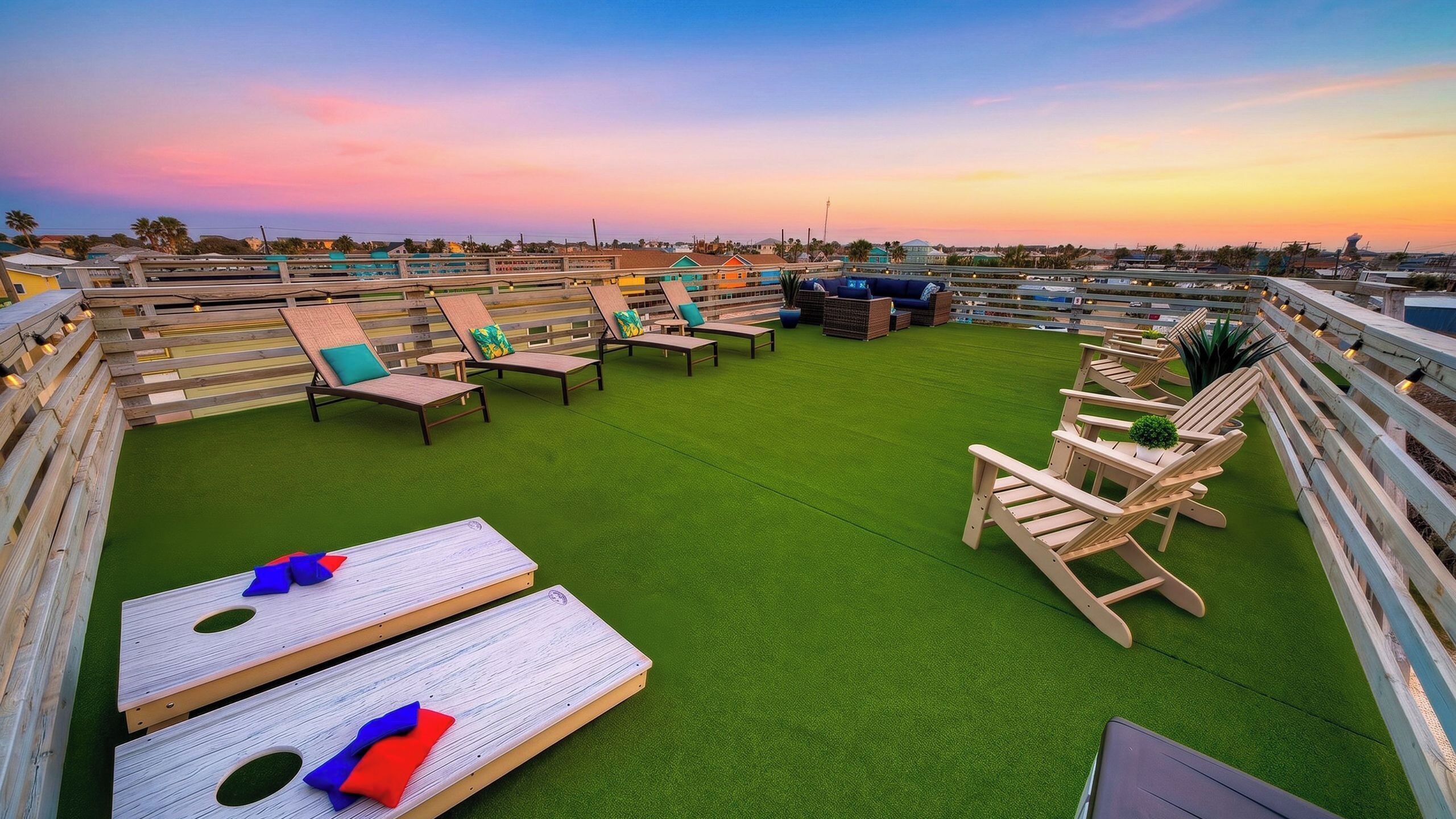 Terraza en la azotea con sillones de descanso, una mesa y vistas al horizonte urbano al atardecer.