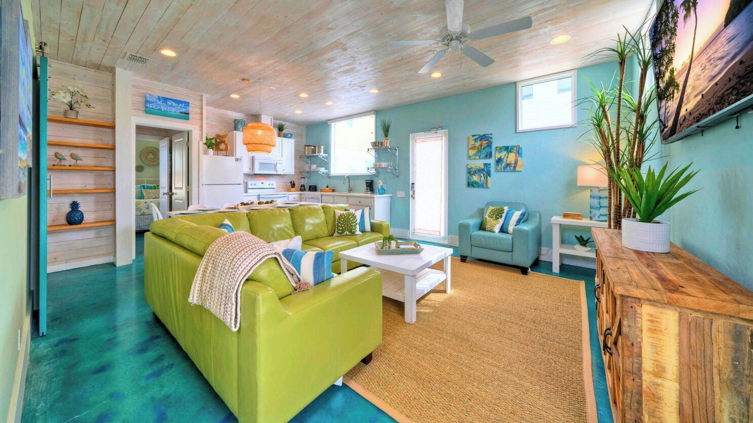 A living room with a green sofa, a white coffee table, and a wooden sideboard.