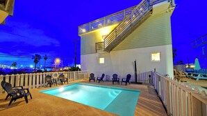 A pool area with chairs and a staircase leading to a balcony. - Stella Maris by Avantstay Rooftop View + Pool (Port Aransas)