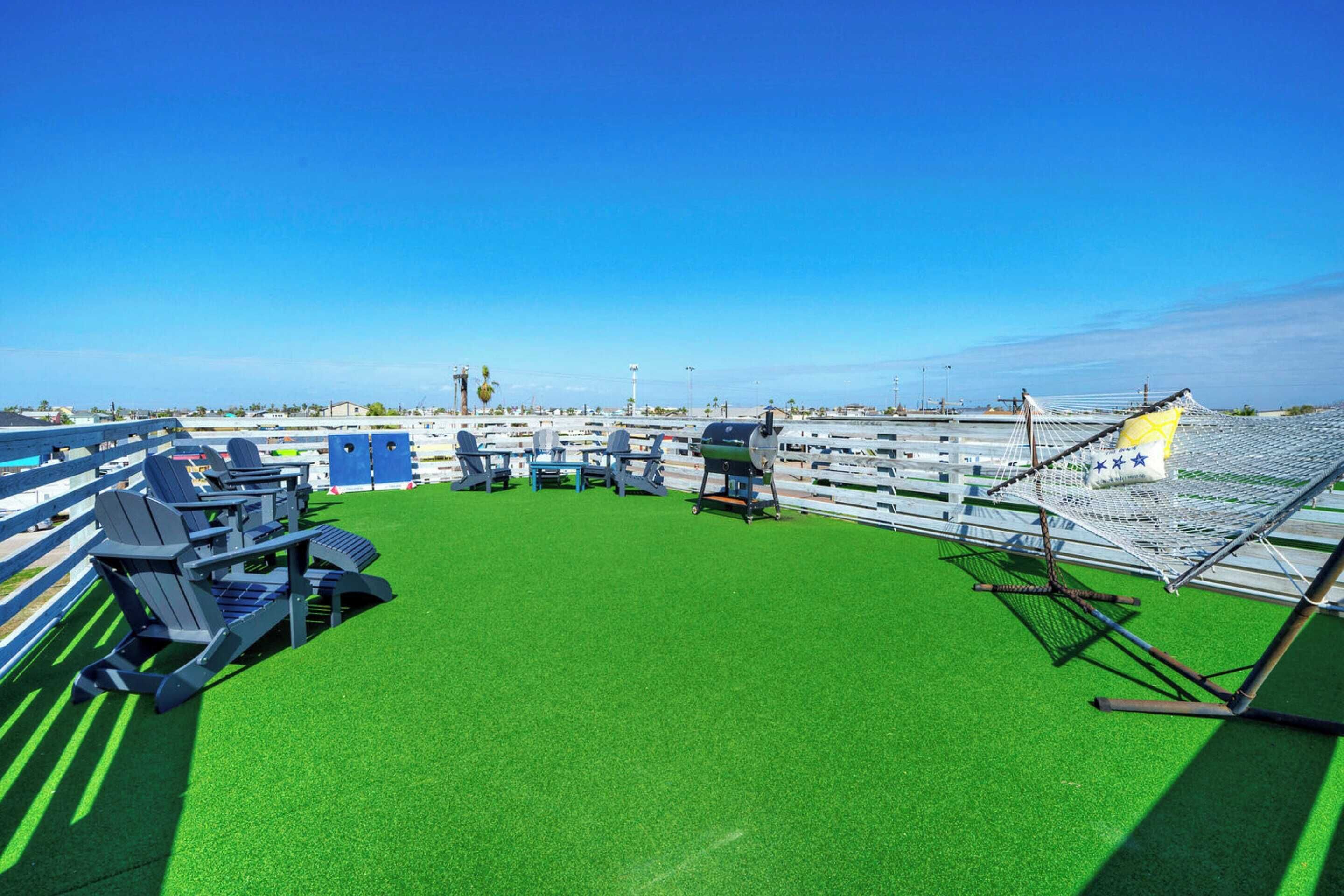 Une terrasse sur le toit, dotée d’une pelouse artificielle verdoyante, d’espaces pour s’asseoir et d’un hamac.
